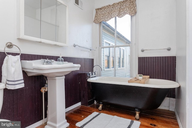 bathroom with wood-type flooring and a tub to relax in