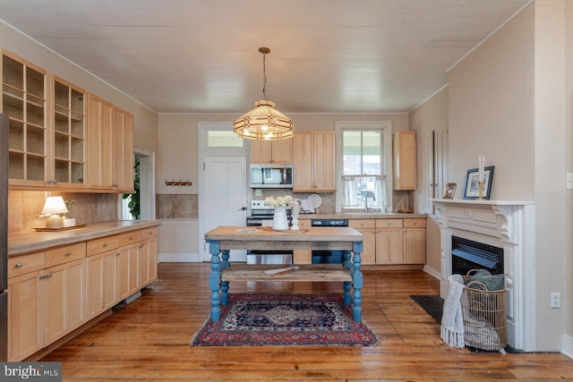 kitchen featuring light brown cabinets, sink, decorative backsplash, light wood-type flooring, and decorative light fixtures