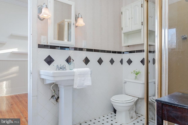 bathroom with tile patterned floors, toilet, and tile walls