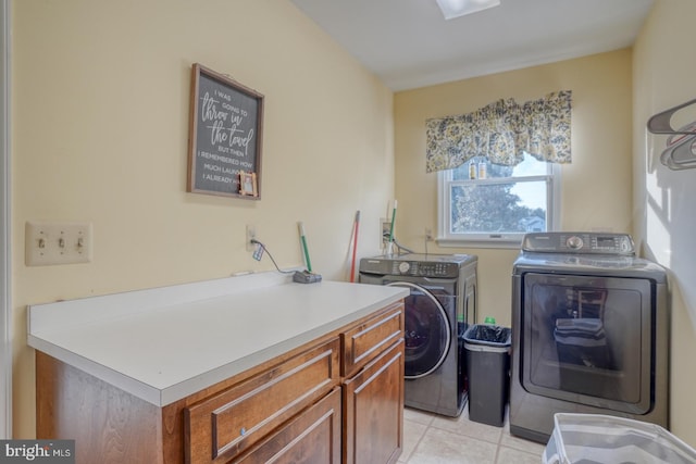 clothes washing area with cabinets, washing machine and dryer, and light tile patterned floors