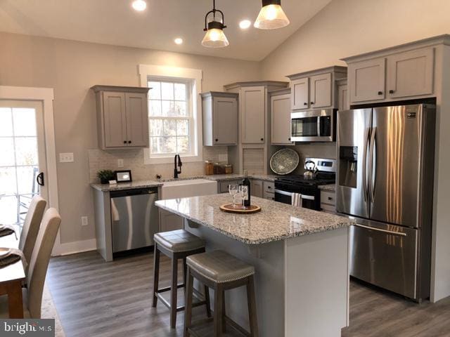 kitchen featuring a center island, sink, hanging light fixtures, dark hardwood / wood-style flooring, and stainless steel appliances