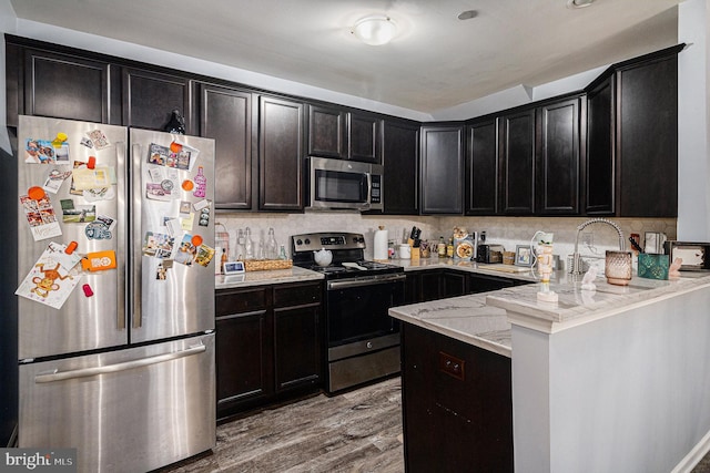 kitchen featuring backsplash, stainless steel appliances, light stone counters, and light hardwood / wood-style floors