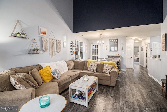 living room with a towering ceiling, an inviting chandelier, and dark wood-type flooring