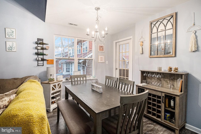 dining area with dark wood-type flooring and a notable chandelier