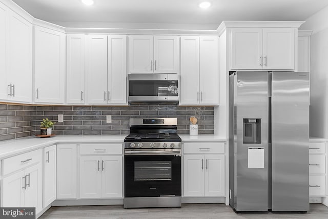 kitchen featuring white cabinets, appliances with stainless steel finishes, tasteful backsplash, and light hardwood / wood-style floors