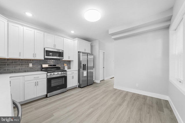 kitchen with tasteful backsplash, white cabinetry, light hardwood / wood-style flooring, and appliances with stainless steel finishes