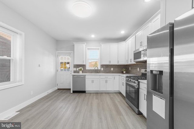 kitchen with light hardwood / wood-style flooring, stainless steel appliances, white cabinetry, and sink