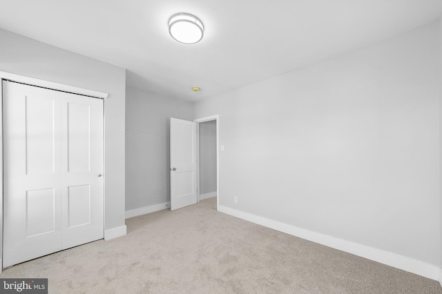 unfurnished bedroom with light carpet and a closet