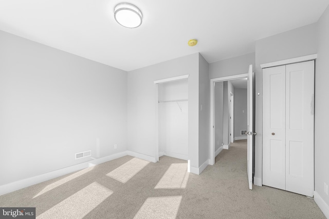 unfurnished bedroom featuring light carpet and multiple closets