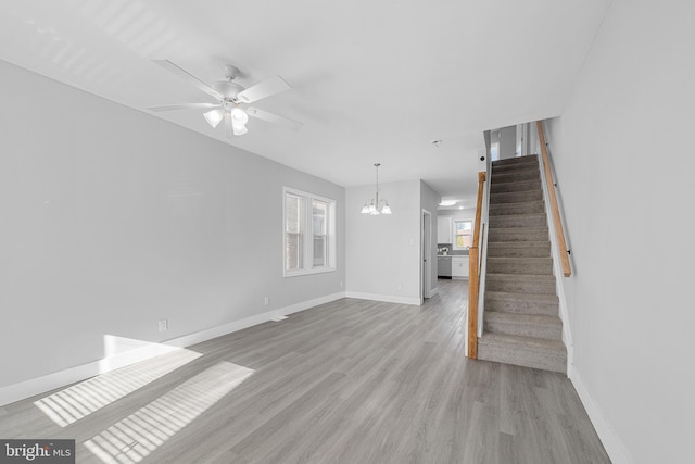 unfurnished living room featuring light wood-type flooring and ceiling fan with notable chandelier