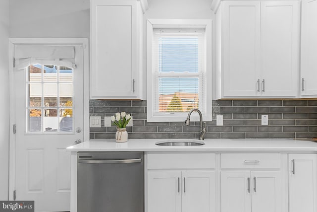 kitchen featuring tasteful backsplash, sink, white cabinets, and stainless steel dishwasher