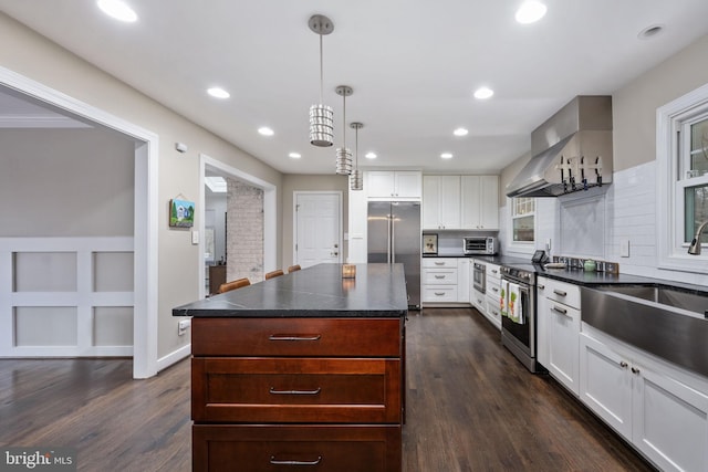 kitchen featuring white cabinets, dark hardwood / wood-style floors, decorative light fixtures, a kitchen island, and appliances with stainless steel finishes