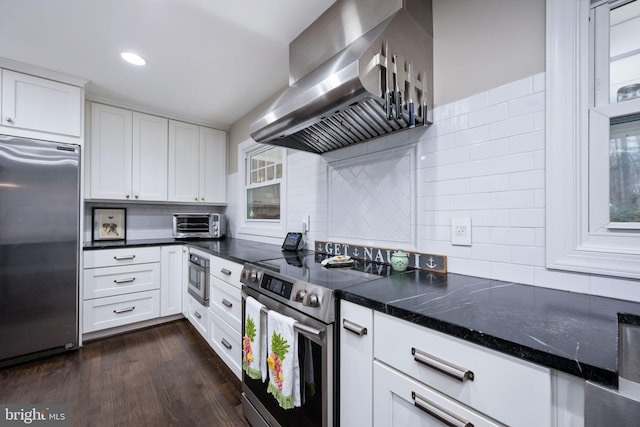 kitchen featuring dark wood-type flooring, white cabinets, tasteful backsplash, range hood, and appliances with stainless steel finishes