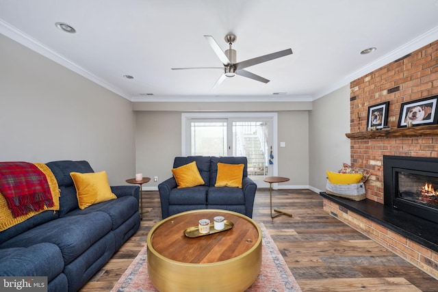 living room featuring dark wood-type flooring, a brick fireplace, ceiling fan, and ornamental molding