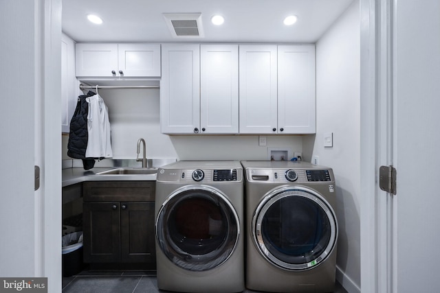 clothes washing area featuring cabinets, dark tile patterned floors, washer and clothes dryer, and sink