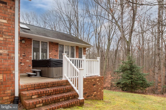 doorway to property featuring a lawn and a hot tub