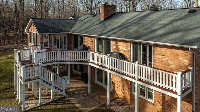 rear view of house featuring a sunroom and a deck