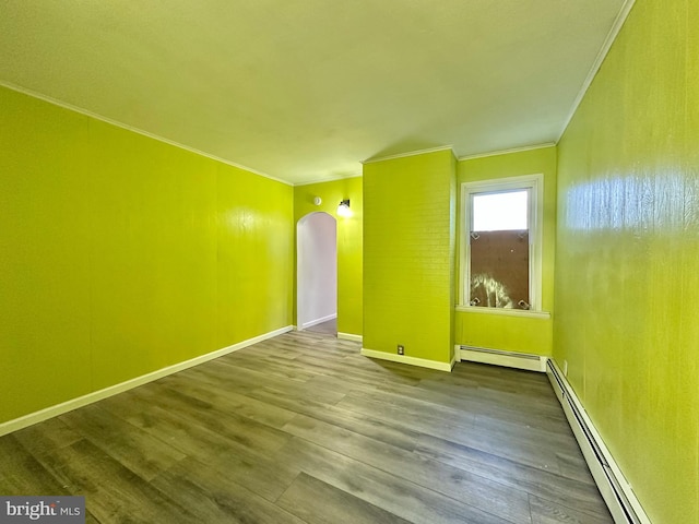 spare room featuring hardwood / wood-style floors, ornamental molding, and a baseboard heating unit