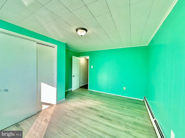 unfurnished bedroom featuring a closet, light hardwood / wood-style floors, and a baseboard radiator