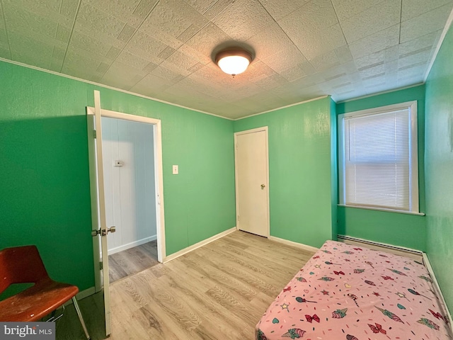 bedroom with hardwood / wood-style flooring and a baseboard heating unit