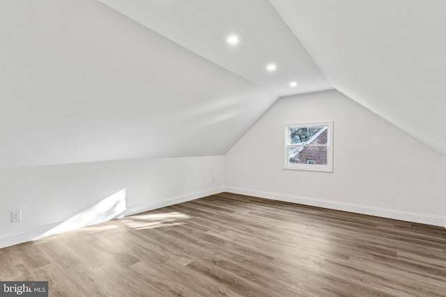 additional living space with hardwood / wood-style floors and vaulted ceiling