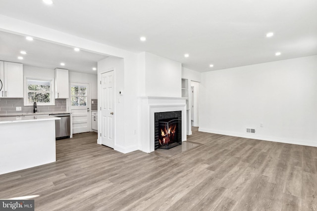 unfurnished living room with sink and light hardwood / wood-style flooring