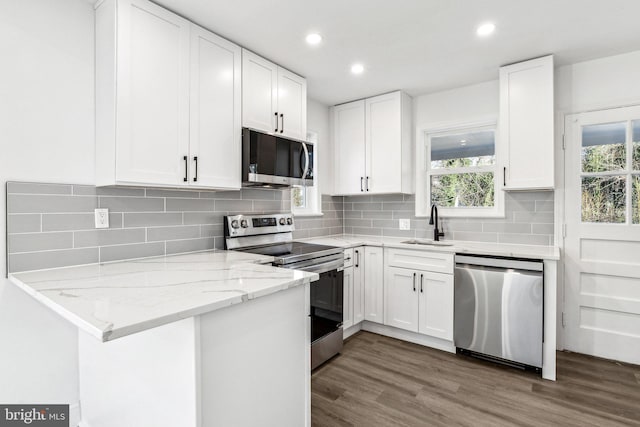 kitchen featuring dark wood-type flooring, sink, white cabinetry, light stone counters, and appliances with stainless steel finishes