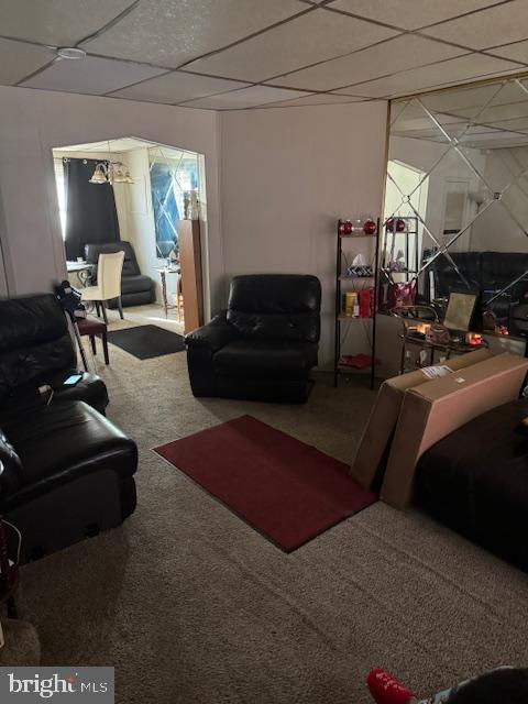 living room with a drop ceiling and carpet floors