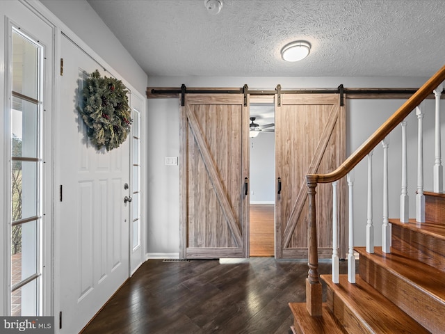 entrance foyer with a textured ceiling, a barn door, and dark hardwood / wood-style floors