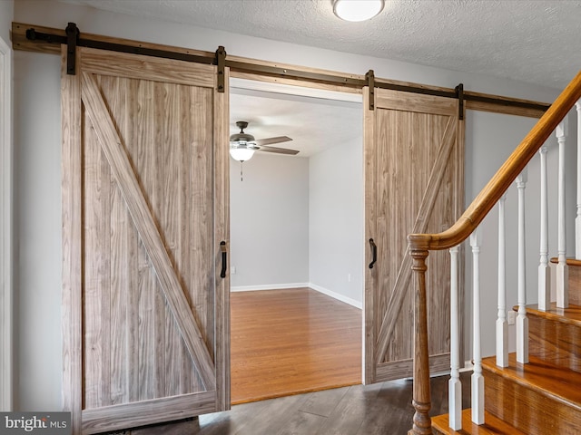 interior space with ceiling fan, a barn door, and a textured ceiling