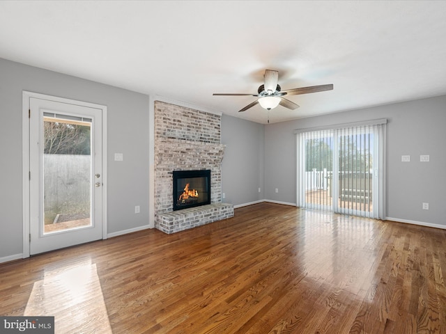 unfurnished living room with hardwood / wood-style flooring, ceiling fan, and a brick fireplace