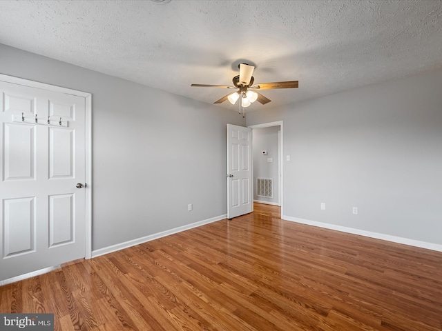 unfurnished bedroom with hardwood / wood-style flooring, ceiling fan, and a textured ceiling