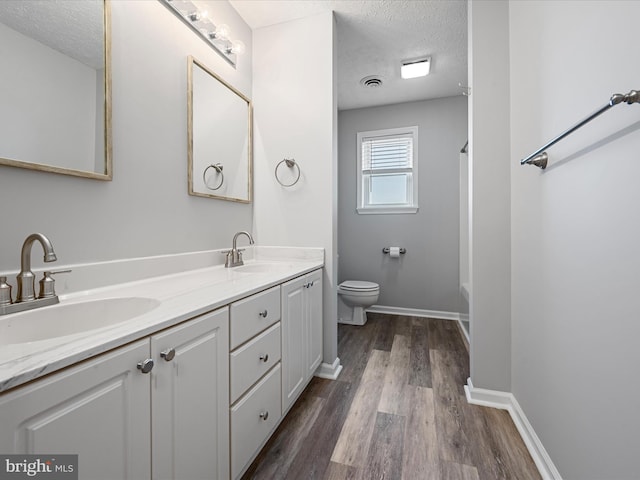 bathroom featuring vanity, a bathtub, toilet, a textured ceiling, and wood-type flooring