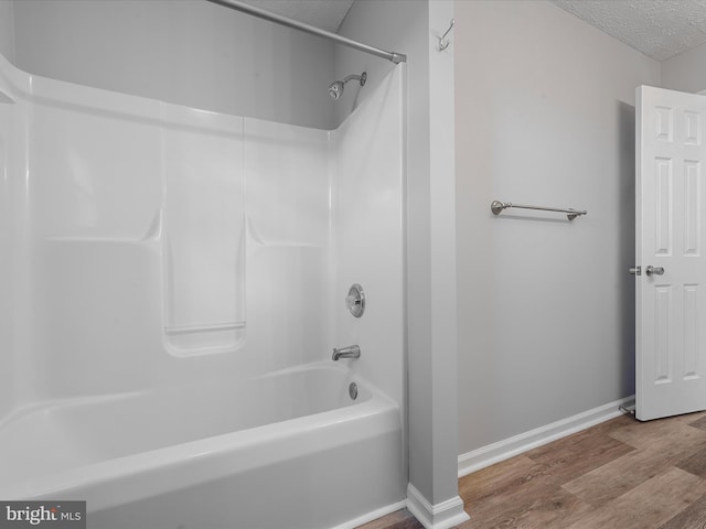 bathroom featuring hardwood / wood-style floors, shower / bath combination, and a textured ceiling