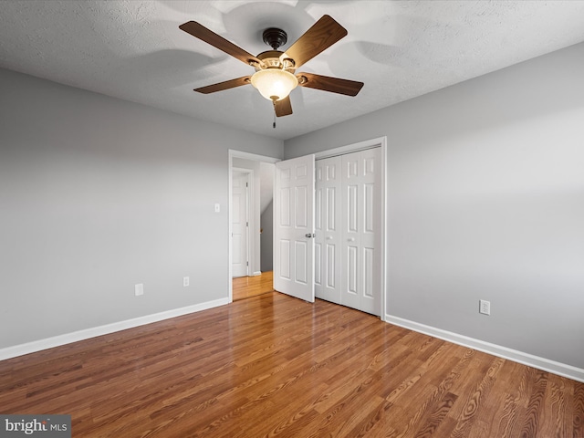 unfurnished bedroom with hardwood / wood-style floors, ceiling fan, a textured ceiling, and a closet