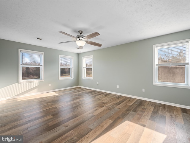 spare room with a textured ceiling, dark hardwood / wood-style flooring, and a healthy amount of sunlight