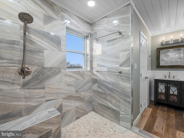 bathroom with crown molding, a tile shower, wood-type flooring, and sink