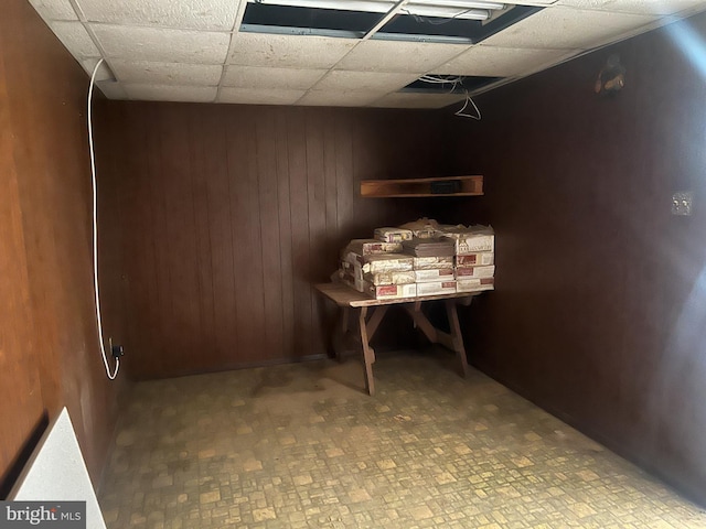 interior space featuring a paneled ceiling and wood walls