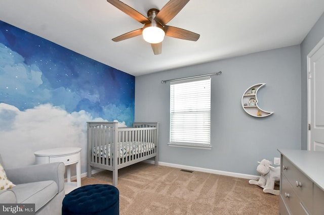 bedroom with light carpet, a nursery area, and ceiling fan