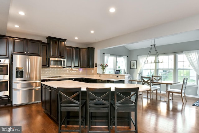 kitchen with a center island, pendant lighting, a breakfast bar area, decorative backsplash, and appliances with stainless steel finishes