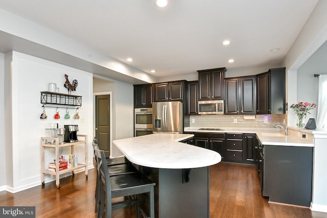 kitchen featuring a center island, backsplash, dark wood-type flooring, a kitchen breakfast bar, and stainless steel appliances