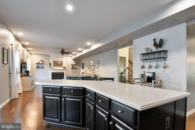 kitchen featuring a fireplace, dark hardwood / wood-style flooring, a kitchen island, and ceiling fan