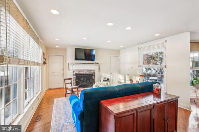 living area with visible vents, recessed lighting, a fireplace, and wood finished floors