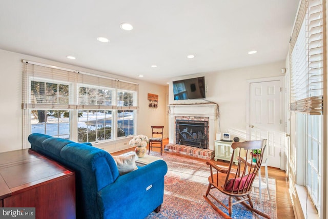 living room with wood finished floors, a brick fireplace, and recessed lighting