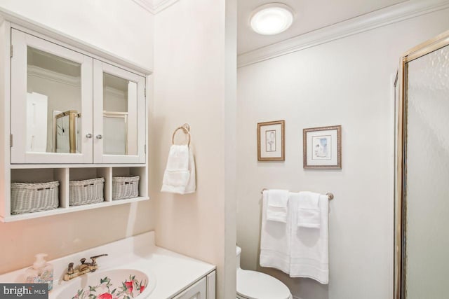 bathroom with vanity, toilet, a shower with door, and crown molding