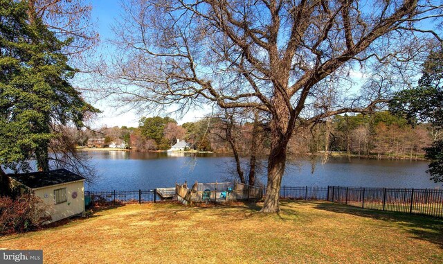 view of yard featuring a water view, an outdoor structure, and fence