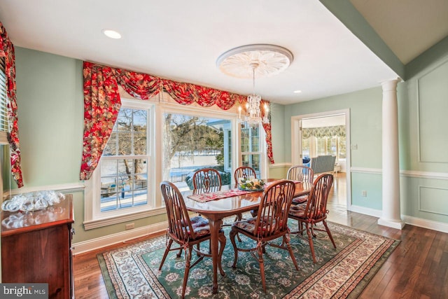 dining space with hardwood / wood-style floors, an inviting chandelier, decorative columns, and baseboards