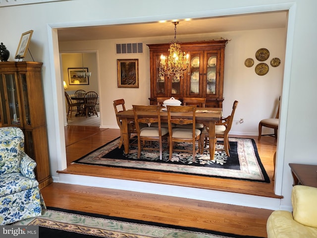 dining space with hardwood / wood-style floors and a chandelier