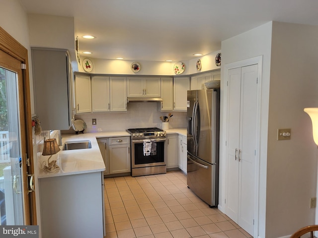 kitchen featuring light tile patterned floors, backsplash, stainless steel appliances, and gray cabinetry