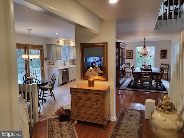 interior space featuring dishwasher, pendant lighting, light wood-type flooring, and an inviting chandelier